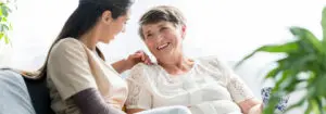Senior woman sitting on couch with nurse
