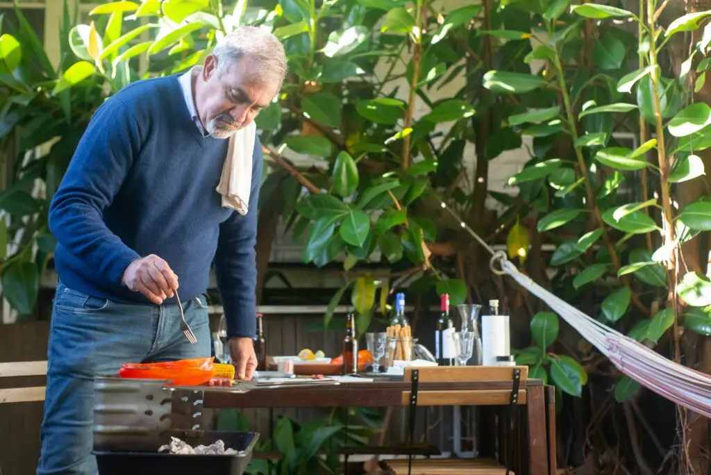 Senior man grilling food outside
