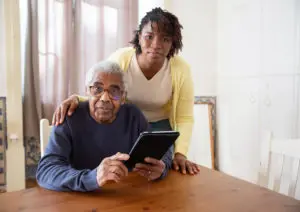 a woman standing behind an older man seated at a table