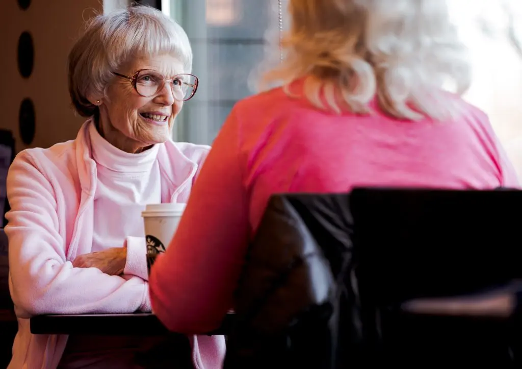 older woman wearing glasses sitting across from another woman