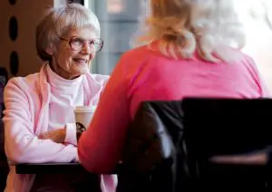 older woman wearing glasses sitting across from another woman
