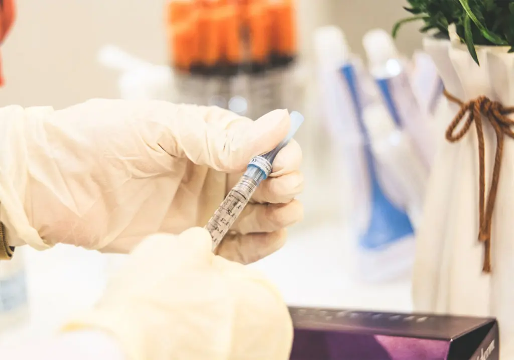 gloved hands holing a syringe