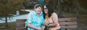 senior mother and adult daughter laughing on bench