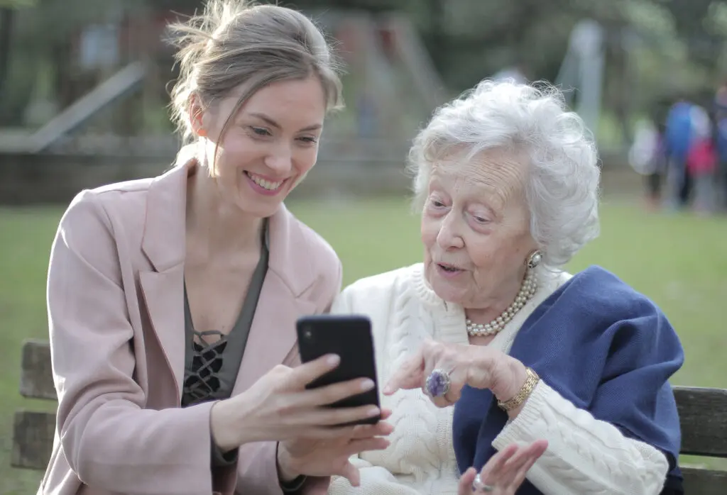 senior mother and adult daughter looking at a smartphone together