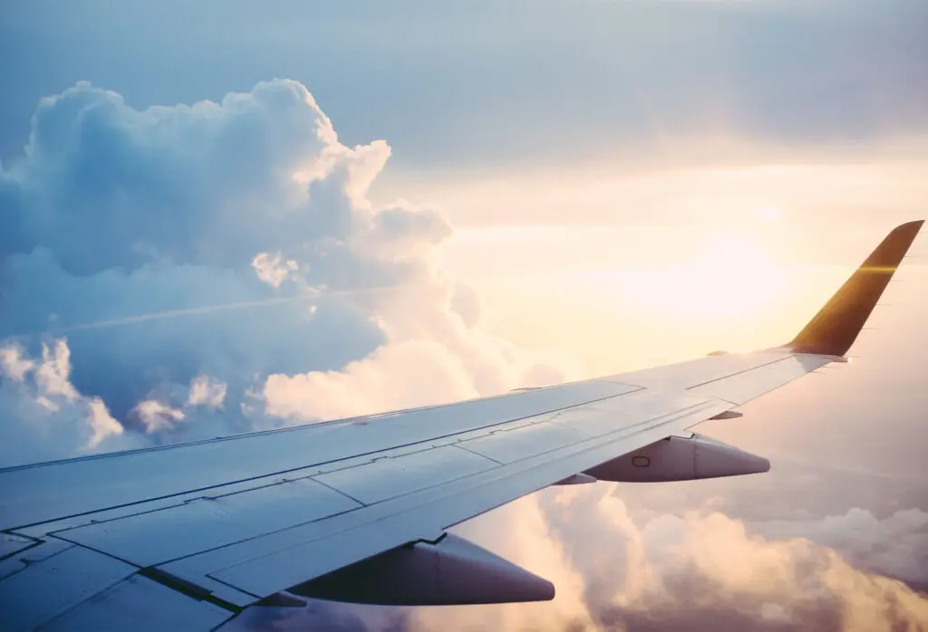 aerial photography of an airplane wing overlooking clouds and the sun
