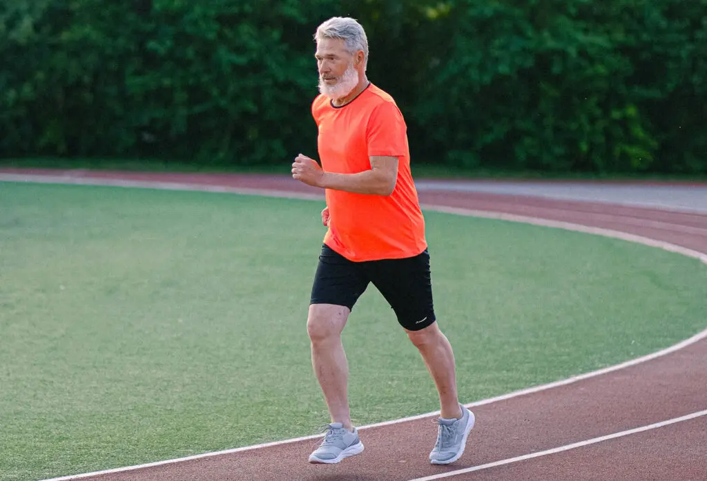 Senior man running on racetrack in stadium