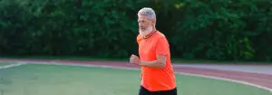 Senior man running on racetrack in stadium