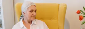 An Elderly Woman Sitting On A Couch Reading A Book