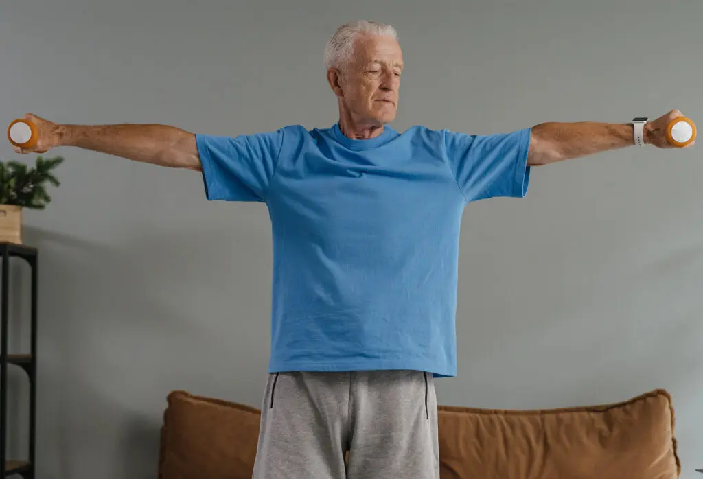A man working out by lifting dumbbells in his living room