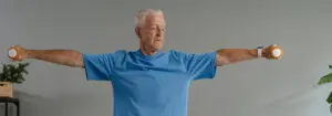 A man working out by lifting dumbbells in his living room
