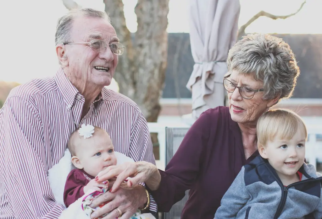 Grandmother and grandfather holding their grandchildren on their lap