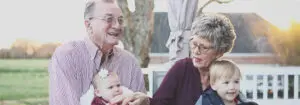 Grandmother and grandfather holding their grandchildren on their lap