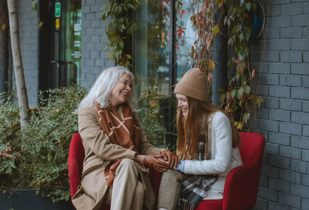 A grandmother and her granddaughter sitting together and holding hands