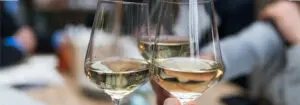 three people having a toast using three clear crystal wine glasses