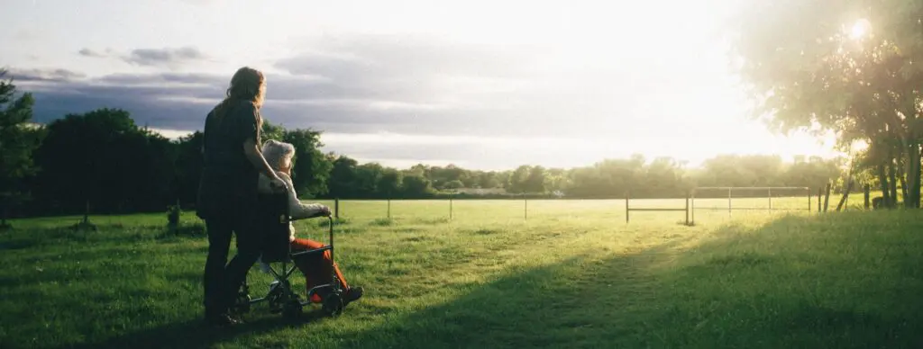 person pushing wheel chair in a field