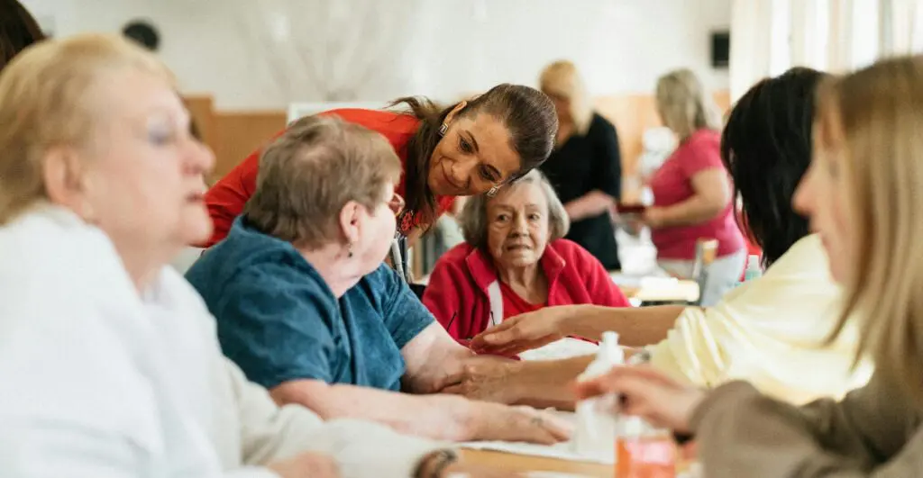 woman talking to elder women sitting at a table