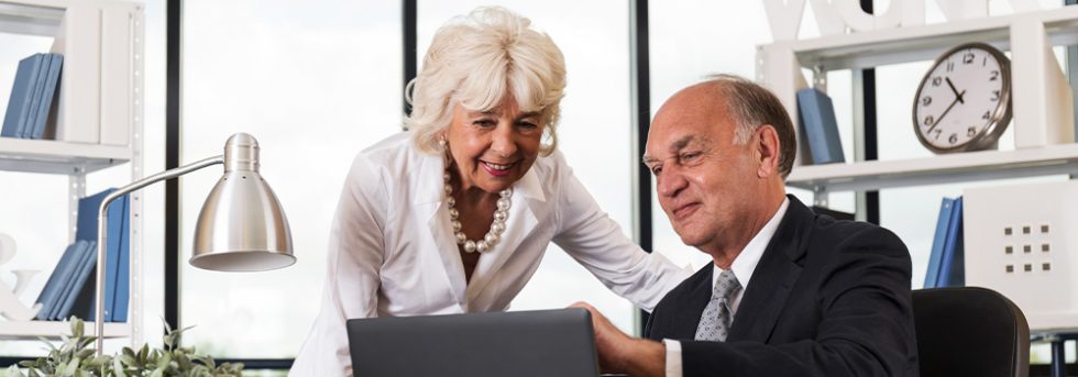 Senior couple looking at laptop in office