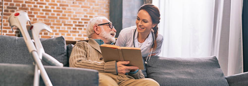 Elderly man holding book and speaking to nurse