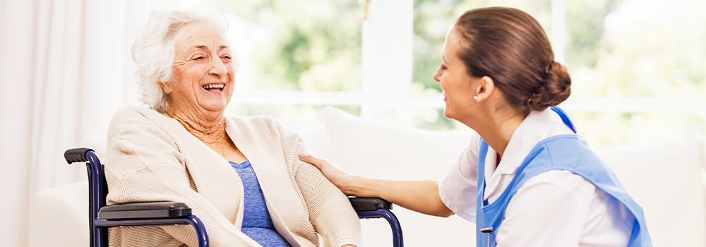Nurse smiling with elderly woman in wheelchair