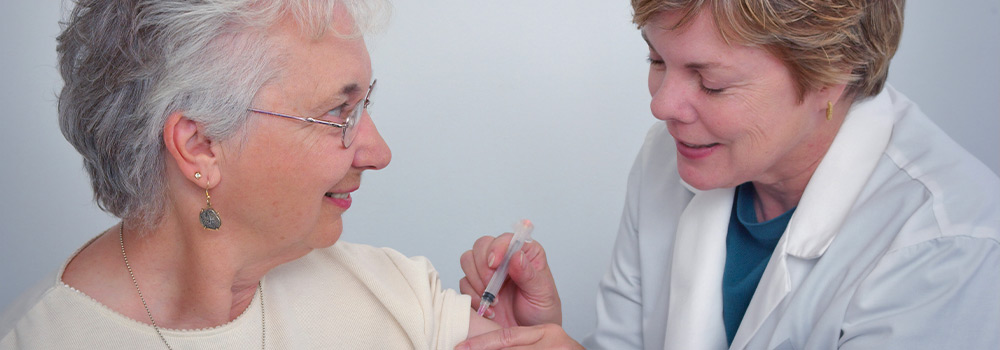 Female doctor giving elderly woman a shot