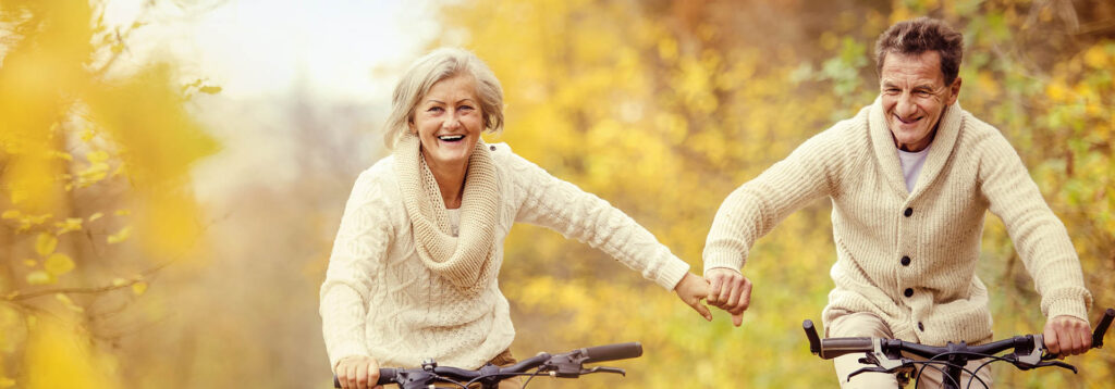 Senior couple riding bikes and holding hands
