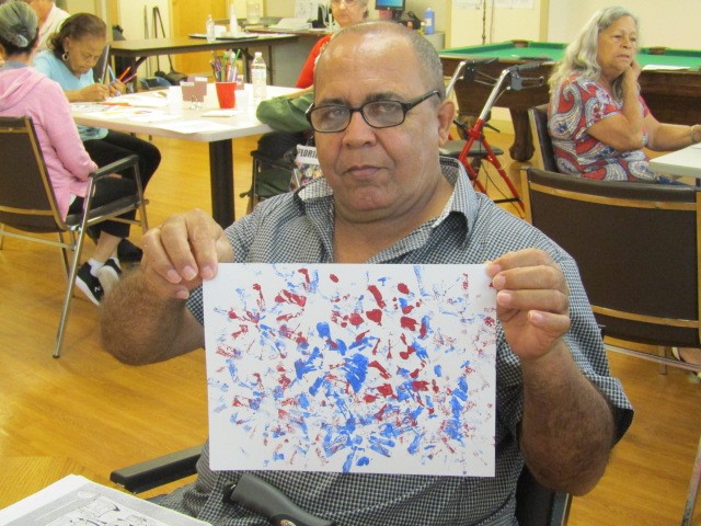 Male PACE participant holding up artwork