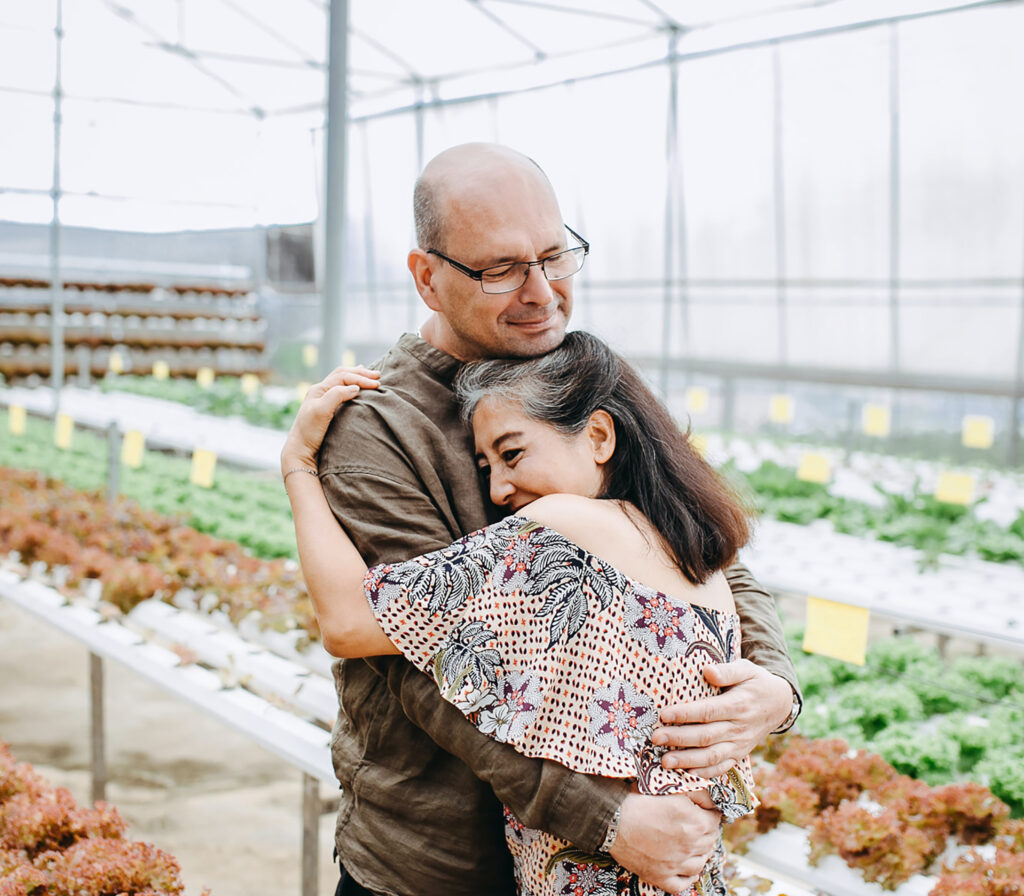 Elderly couple hugging in greenhouse