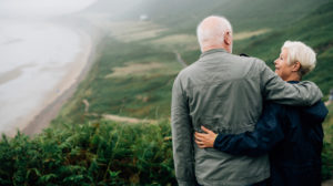Elderly couple standing on hill near beach