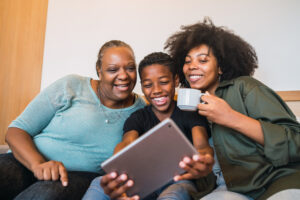 Grandmother, grandson, and daughter smiling at iPad