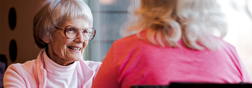 older woman wearing glasses sitting across from another woman