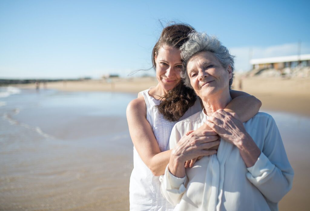 old woman and adult daughter on beach
