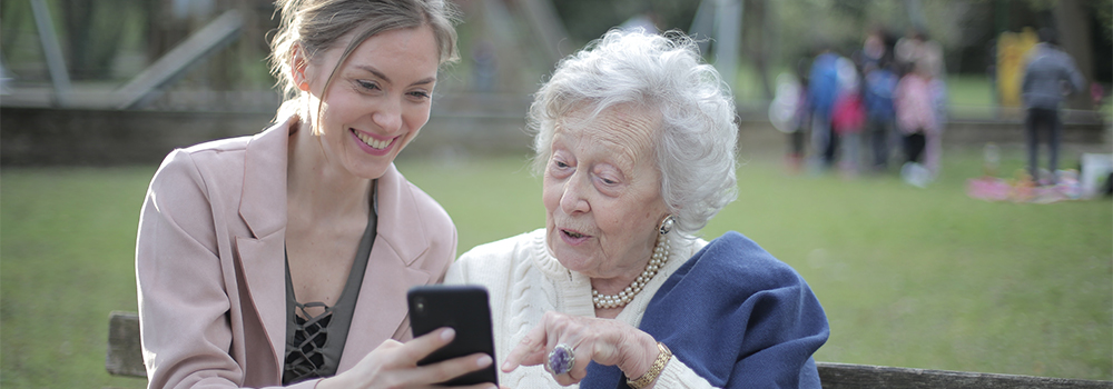 senior mother and adult daughter looking at a smartphone together