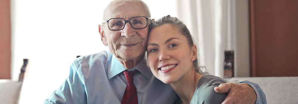 Elderly man smiling  sitting with his arm around his granddaughter