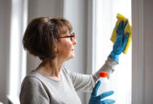 A woman wearing gloves and cleaning a window with cloth